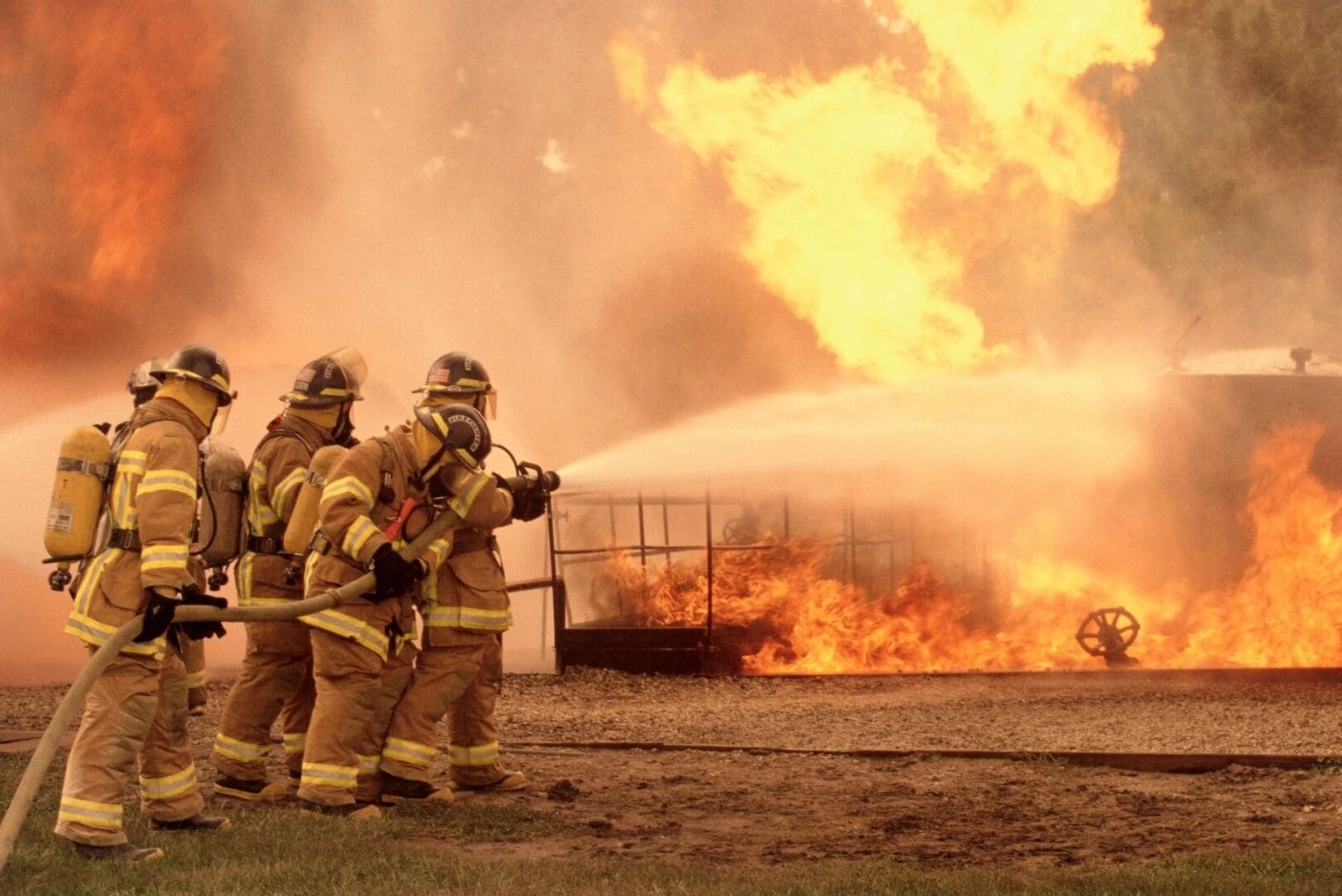 A group of firefighters standing next to a fire.
