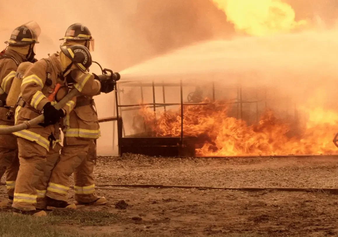 A fire fighter spraying water on a burning building.